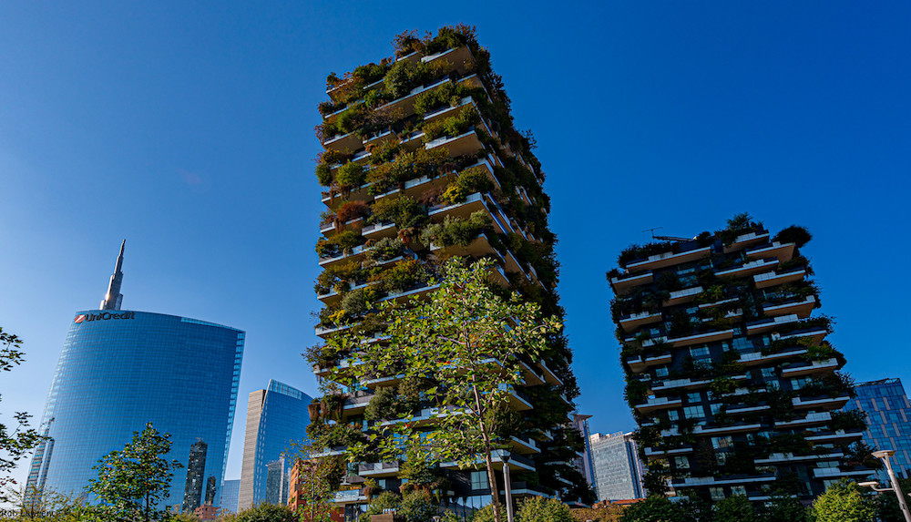 Image of two tower buildings, each covered in trees and plants.